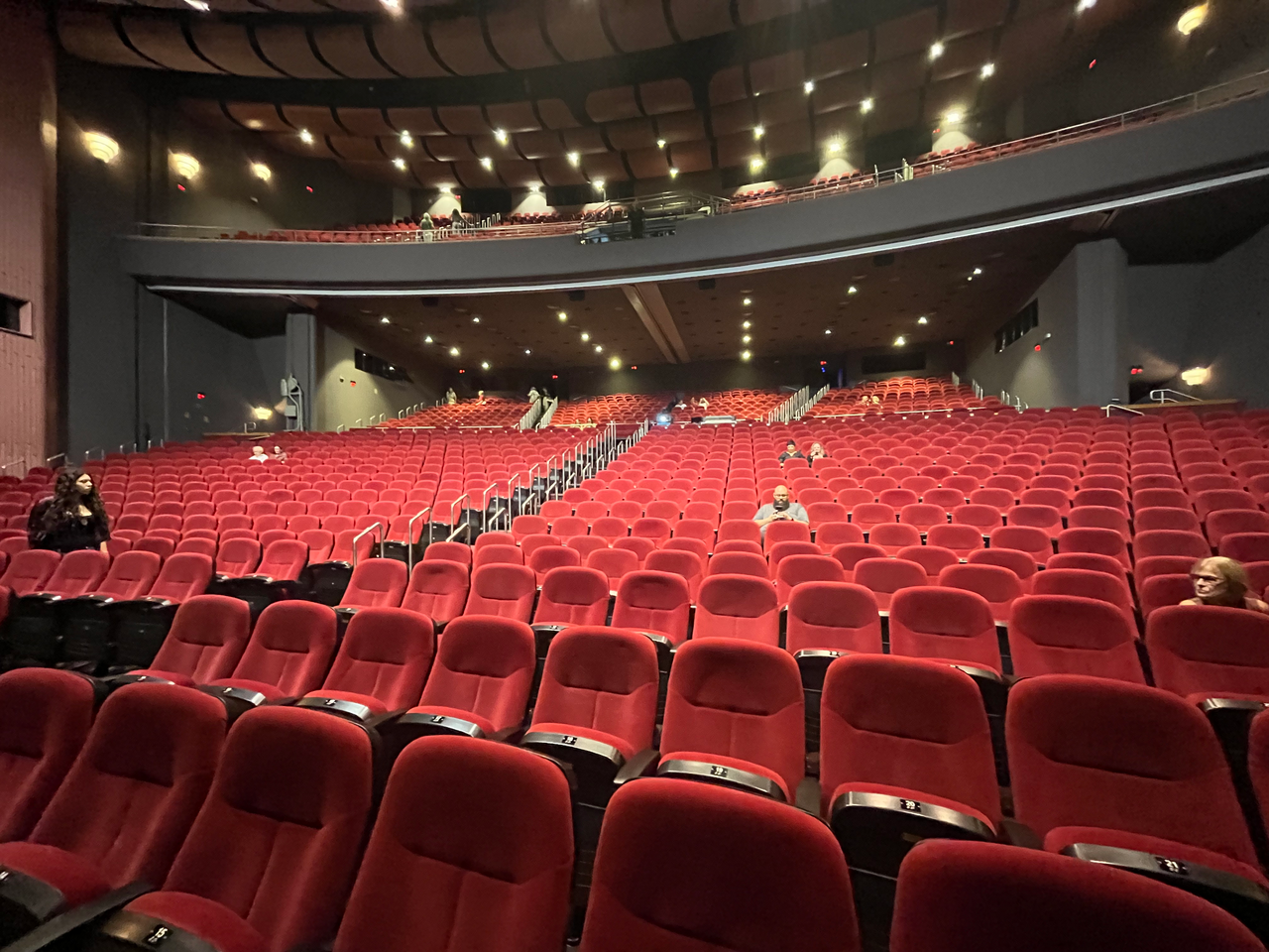 Poltronas vermelhas da plateia de um teatro antes do início do espetáculo