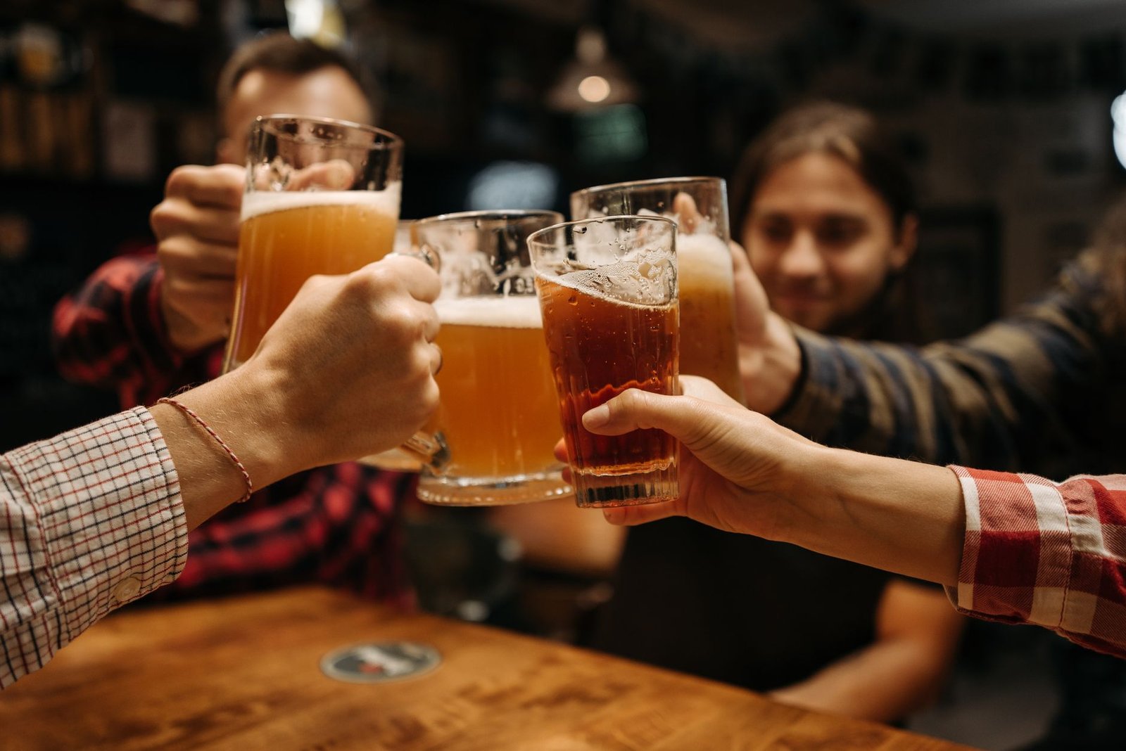 Brinde de amigos com copos de cerveja em uma mesa de bar