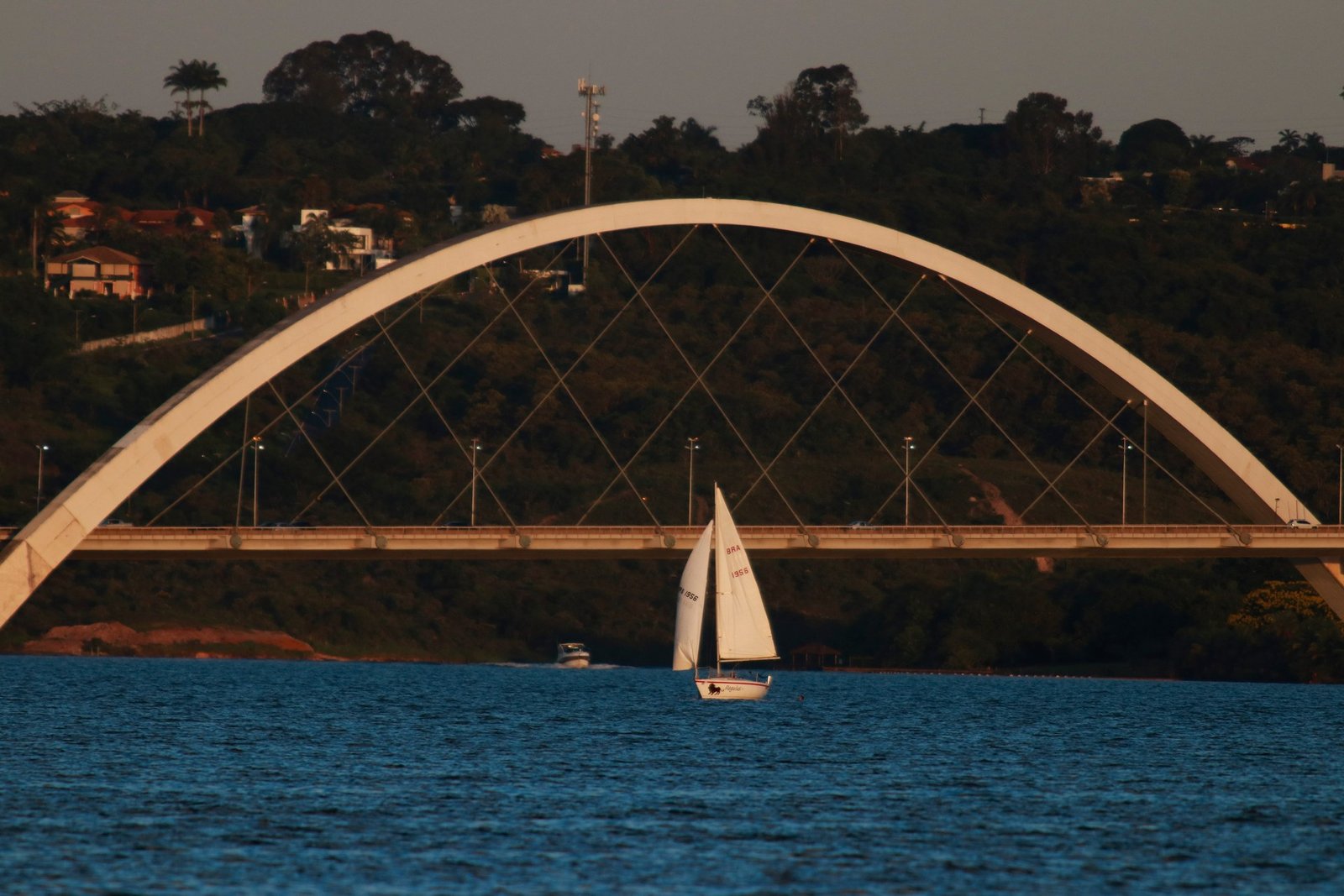 Arco da Ponte JK sobre o Lago Paranoá com um veleiro ao fim da tarde, foto de arquivo