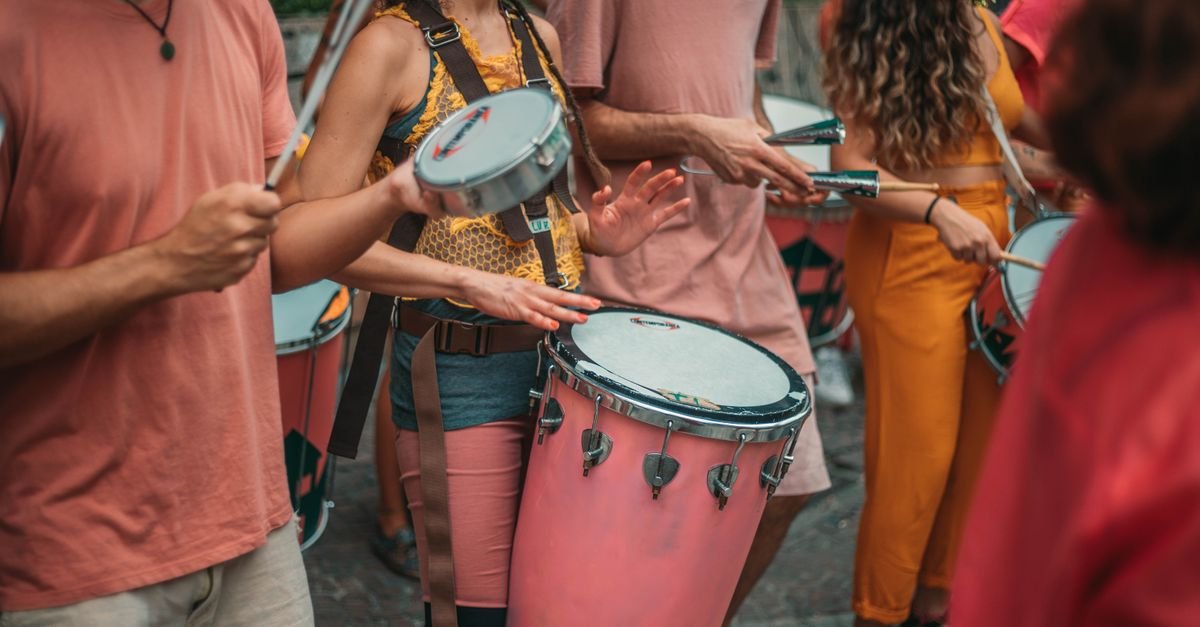 Grupo de percussionistas tocando surdo, tamborim e repique em apresentação de rua