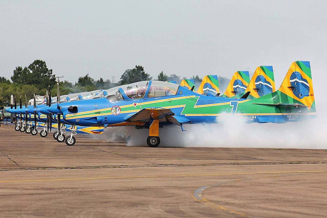Aeronaves A-29 Super Tucano da Esquadrilha da Fumaça alinhadas na pista com fumaça branca