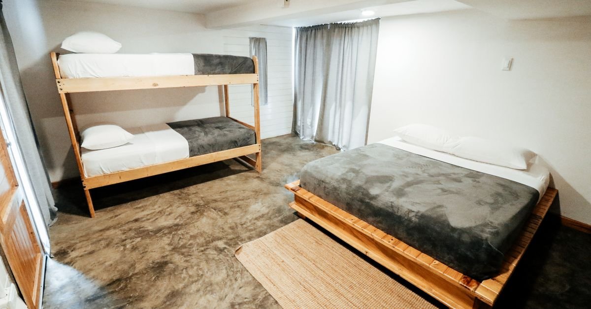 Quarto com beliche de madeira e cama de casal em hospedagem