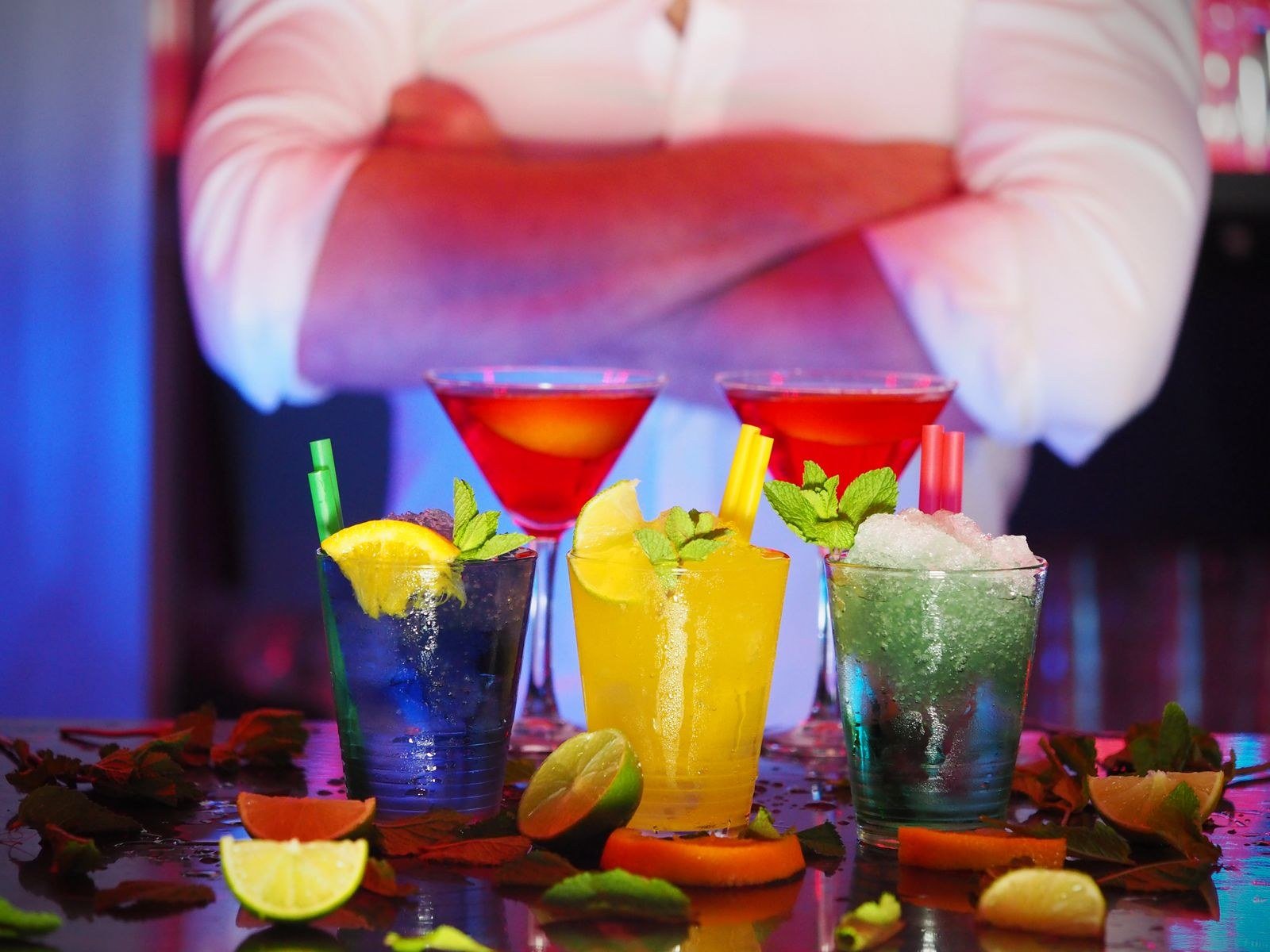 Drinques coloridos com frutas e hortelã sobre o balcão de um bar