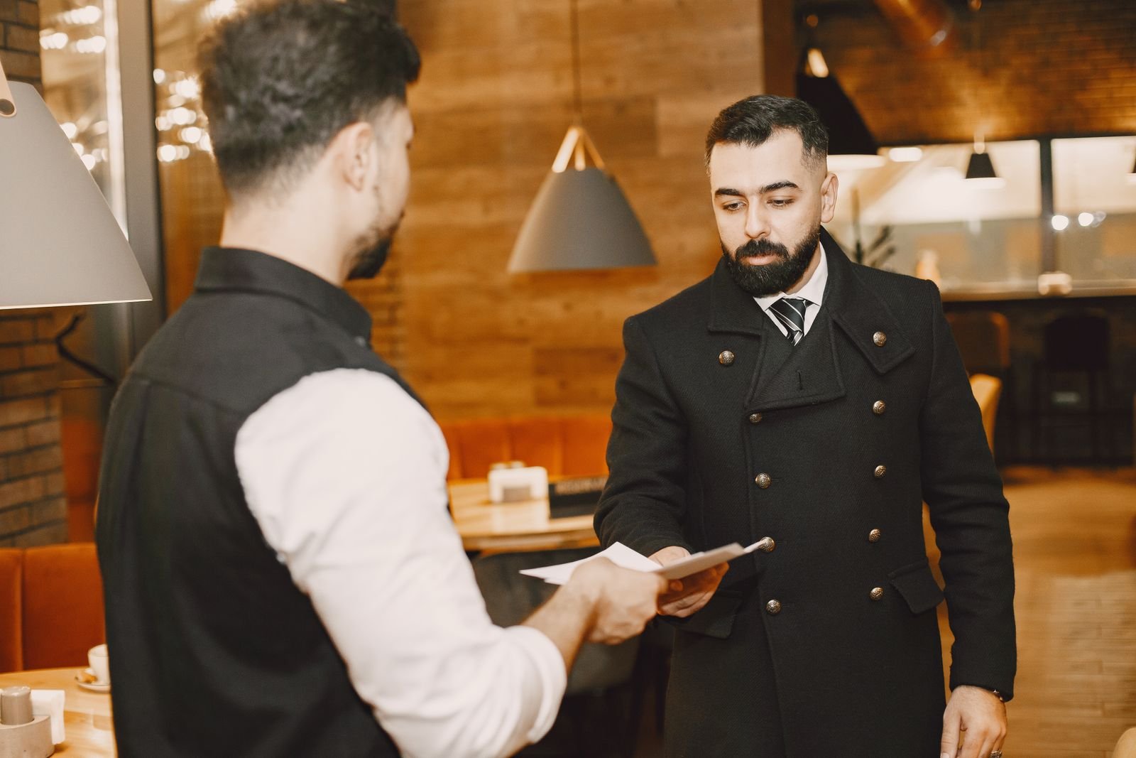 Garçom entrega documentos a um homem em restaurante