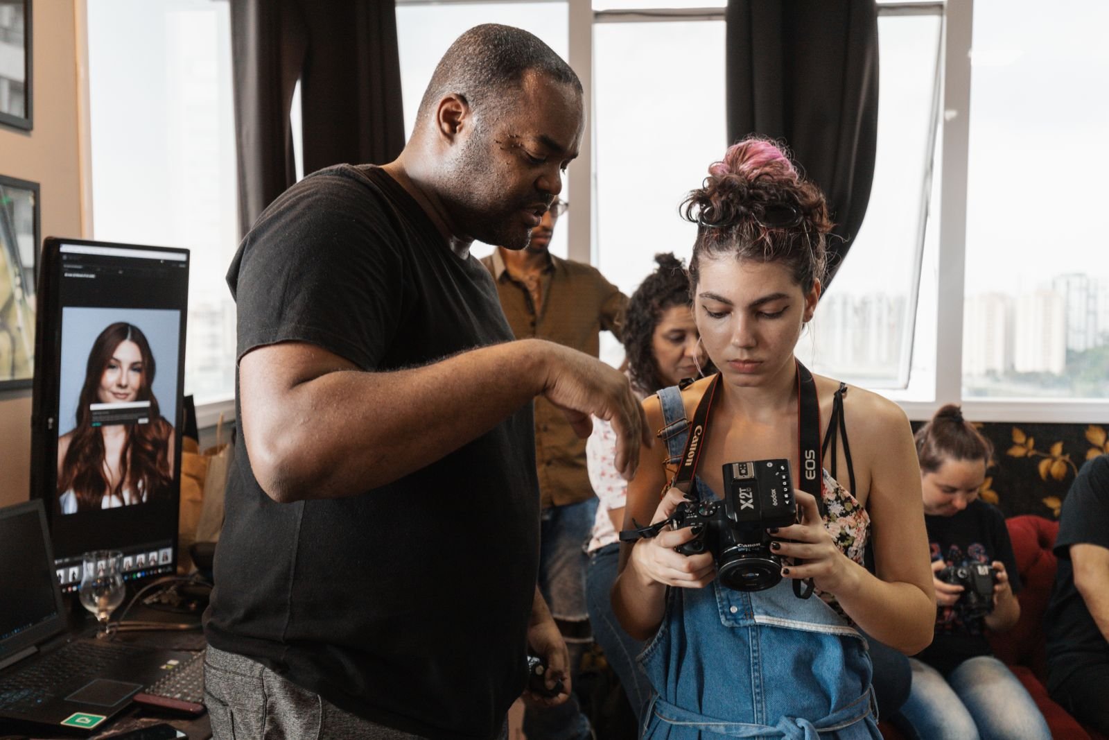 Instrutor orienta aluna com câmera em oficina de fotografia