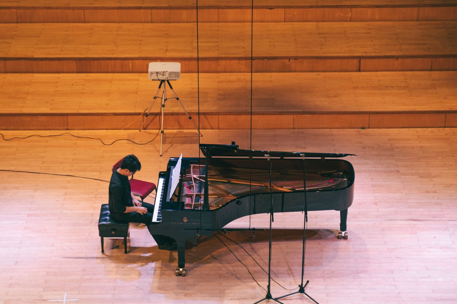 Pianista toca piano de cauda em palco de madeira vista do alto
