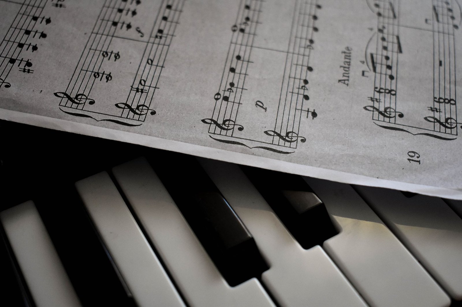 Partitura de piano com a indicação Andante apoiada sobre as teclas de um piano