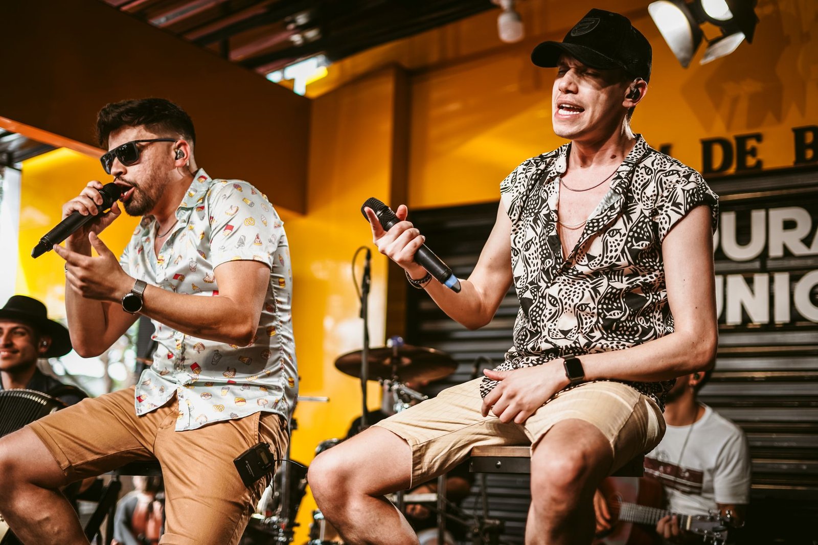 Dois cantores com microfone em apresentação ao vivo de pagode, foto ilustrativa de banco de imagens