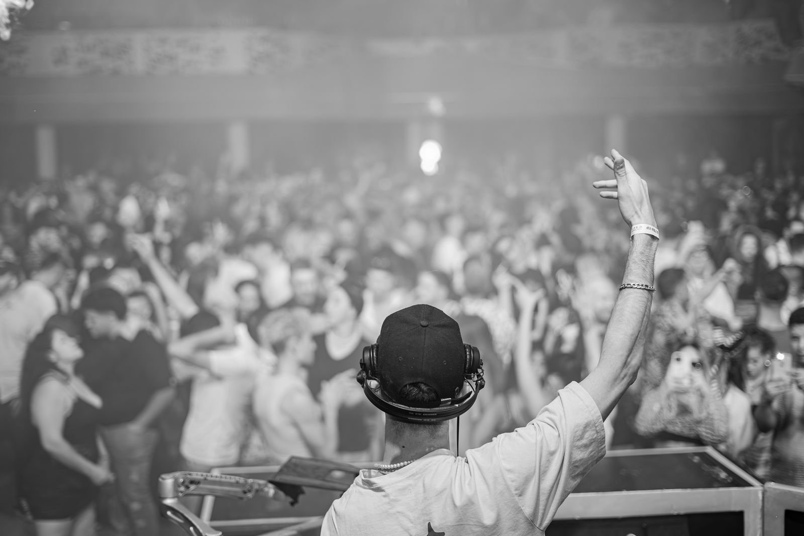 DJ de costas, com o braço erguido, diante de pista cheia em casa noturna (foto ilustrativa, não é do Anexo BZ)