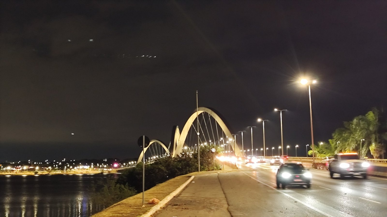 Ponte JK iluminada à noite, vista da margem do Lago Paranoá, em Brasília