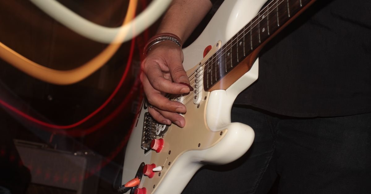 Guitarrista tocando guitarra elétrica branca durante show