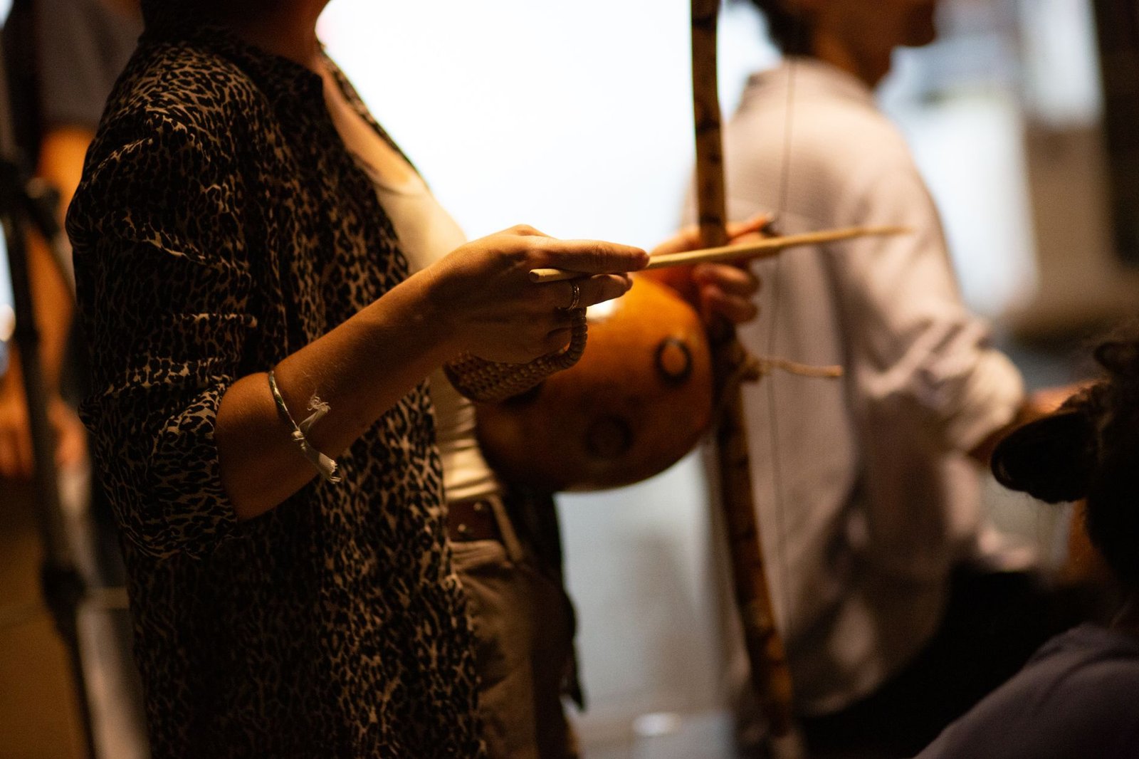 Mãos de músico segurando a baqueta junto ao berimbau durante roda de capoeira