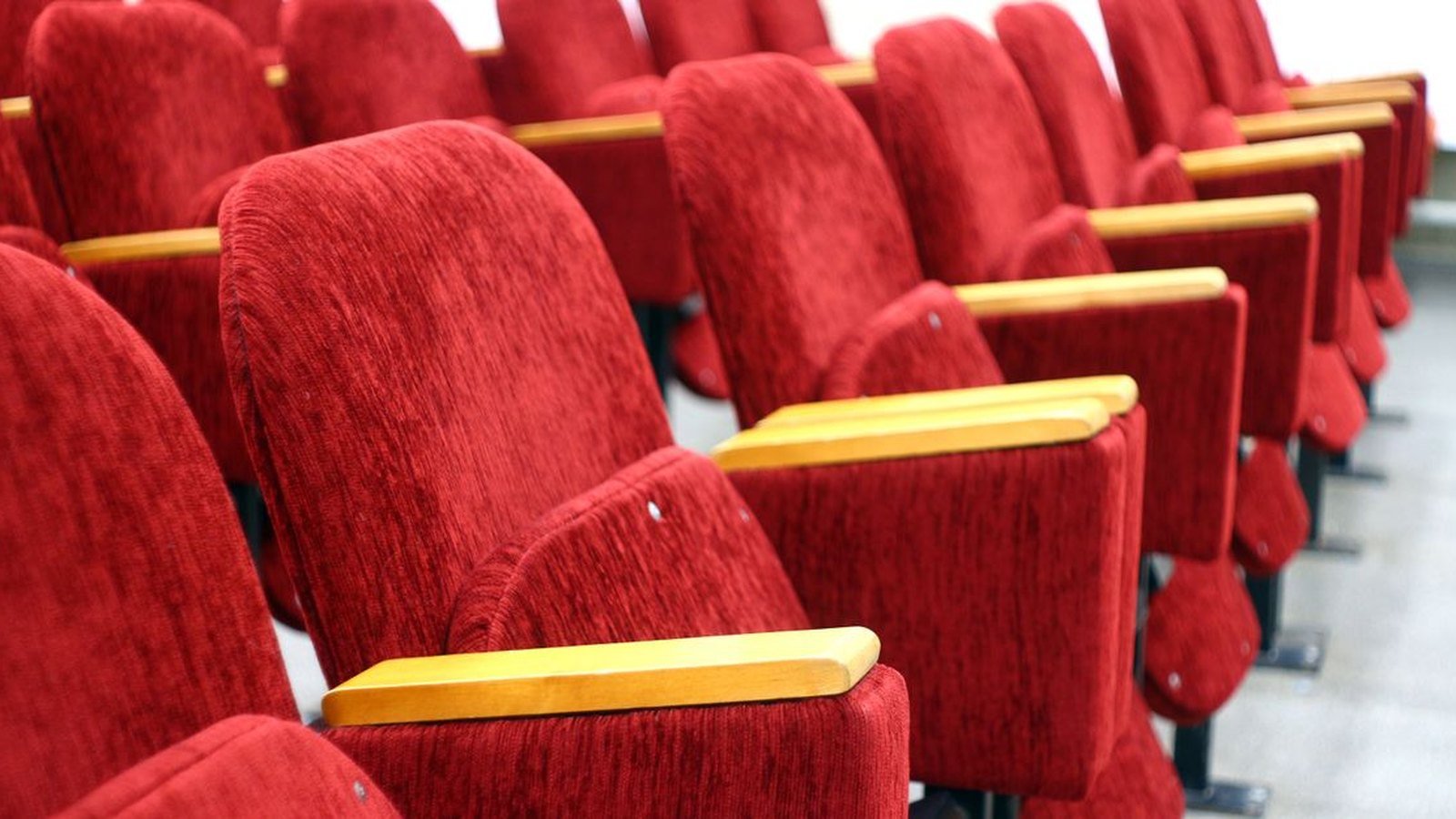 Fileiras de poltronas vermelhas vazias em plateia de teatro