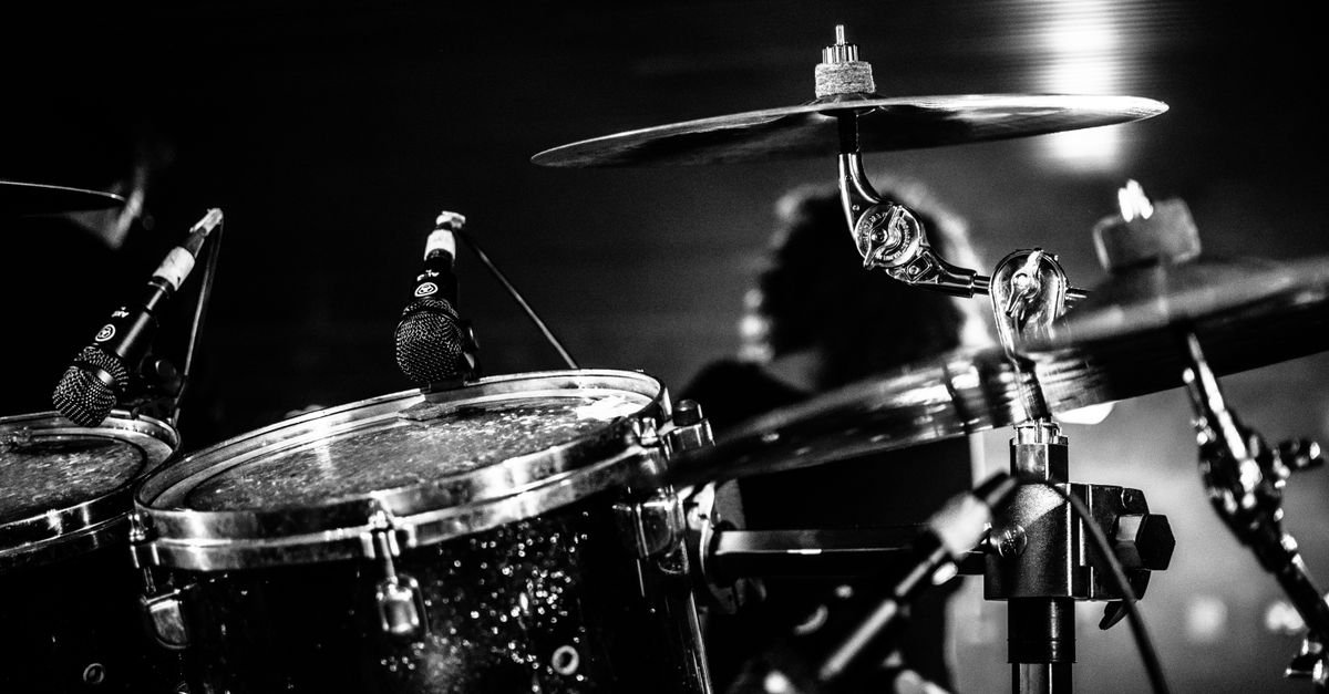 Kit de bateria com microfones em palco, em preto e branco