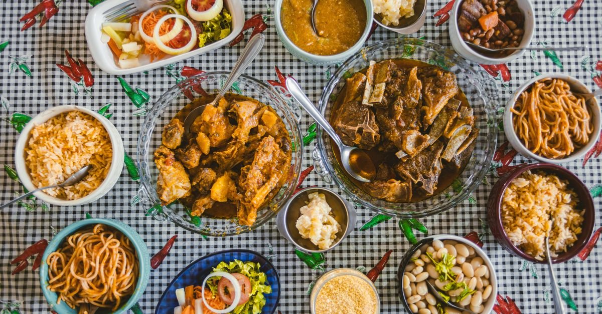 Mesa vista de cima com pratos de comida brasileira, arroz, feijão, farofa e carnes