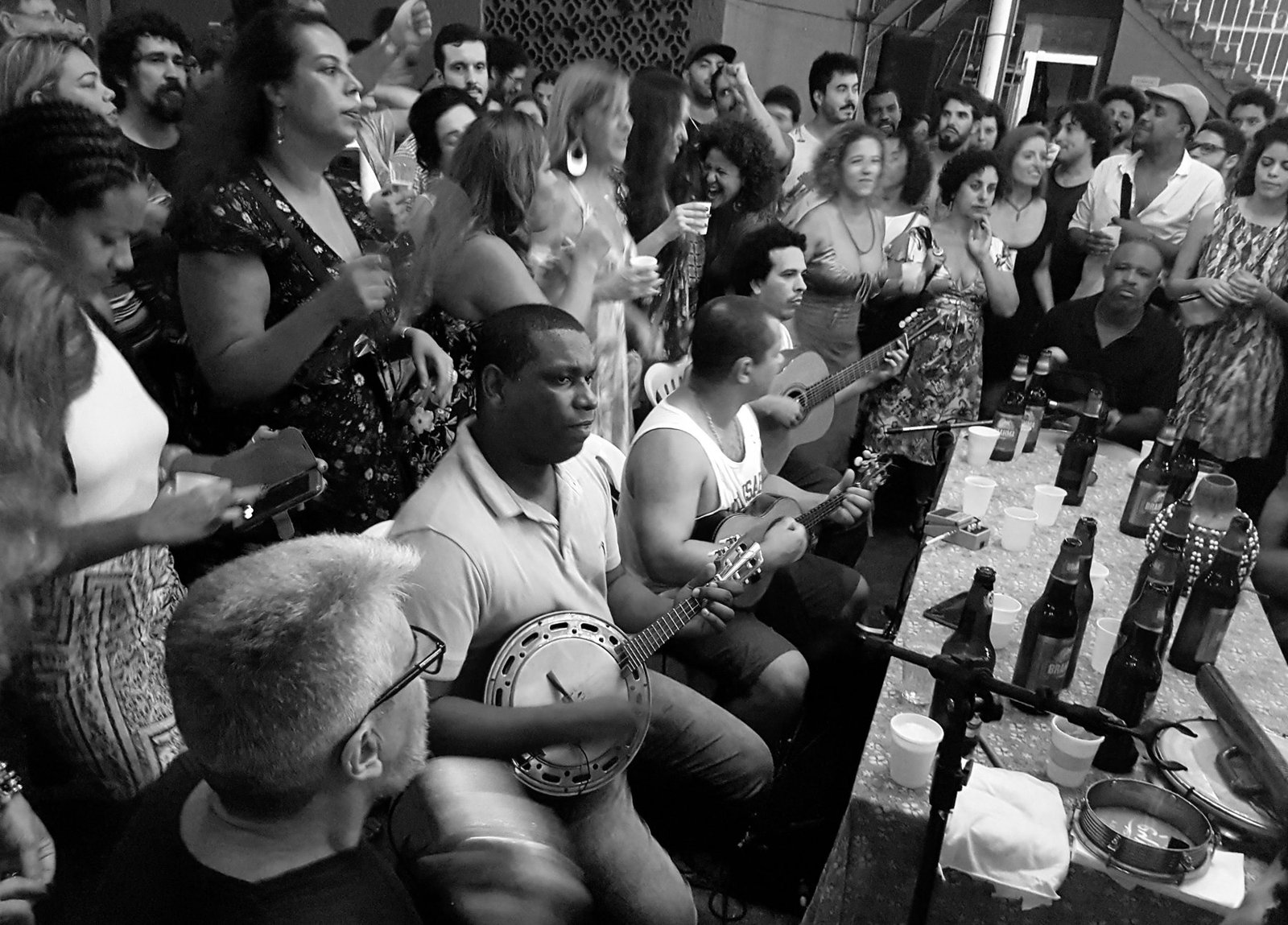 Roda de samba com músicos tocando banjo e violão e público cantando em volta, em preto e branco (foto de arquivo de uma roda no Rio de Janeiro, não é da Ursal)