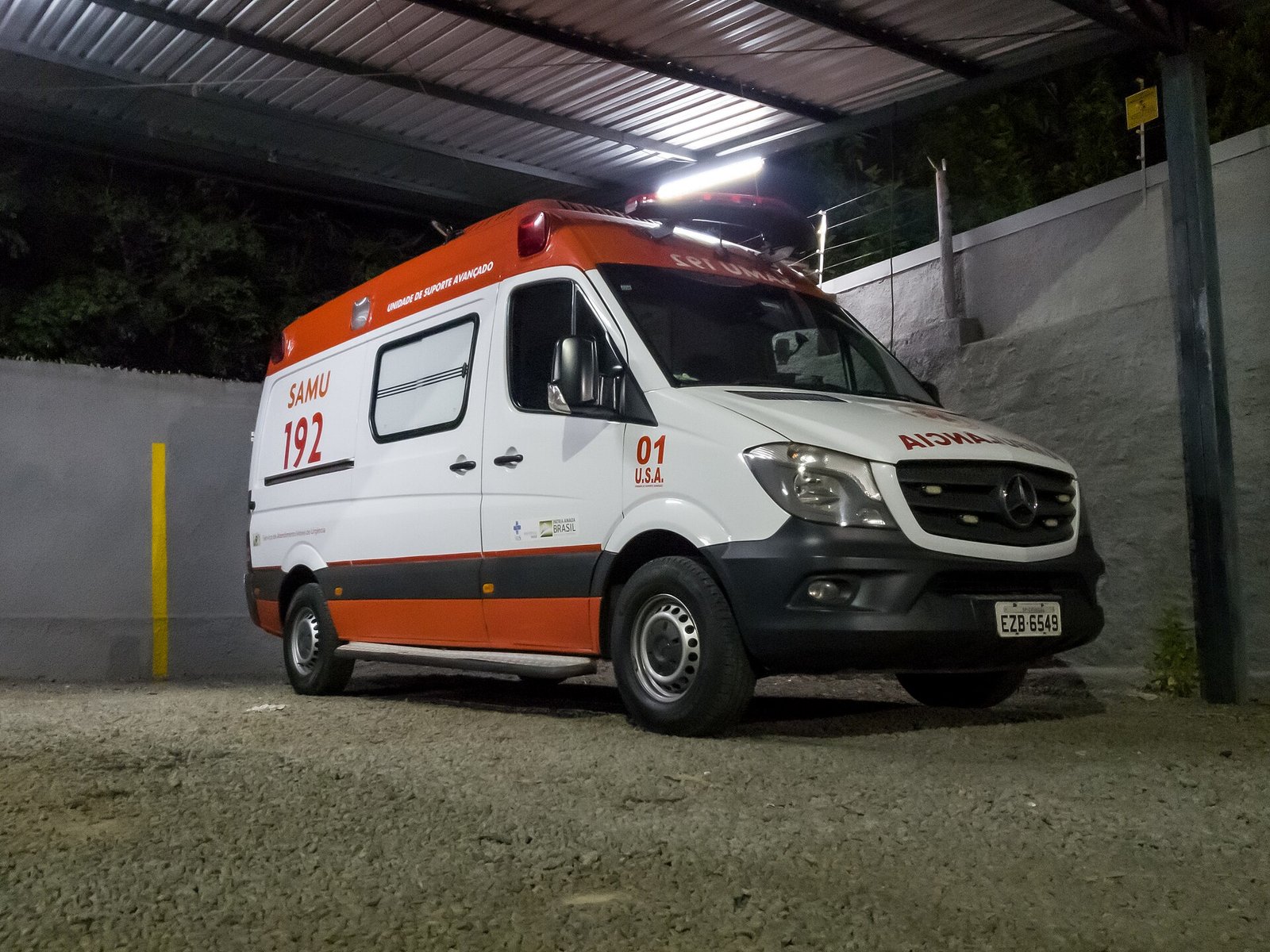 Ambulância do Samu 192 estacionada sob uma cobertura, com a lateral e a frente visíveis