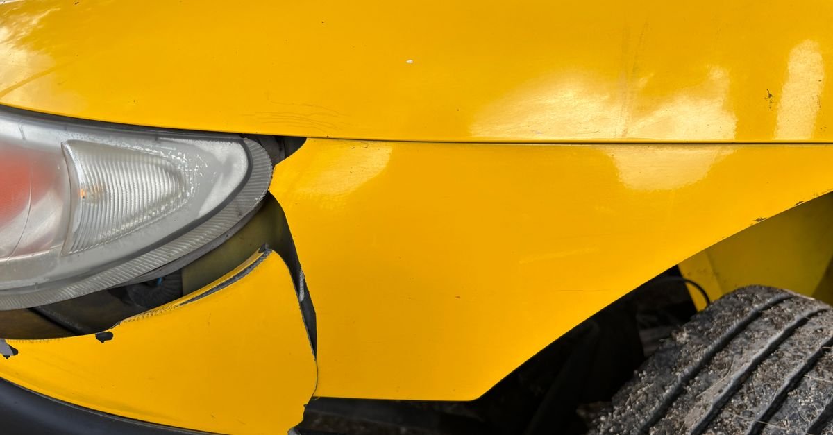 Closeup da frente amassada de um carro amarelo apos colisao