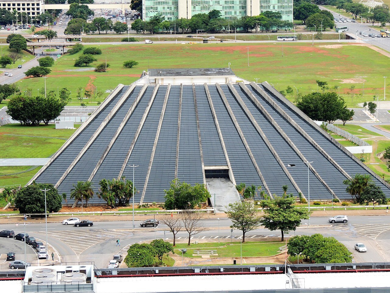 Vista aérea do Teatro Nacional Cláudio Santoro, em Brasília, com a fachada em forma de pirâmide e o Eixo Monumental ao fundo