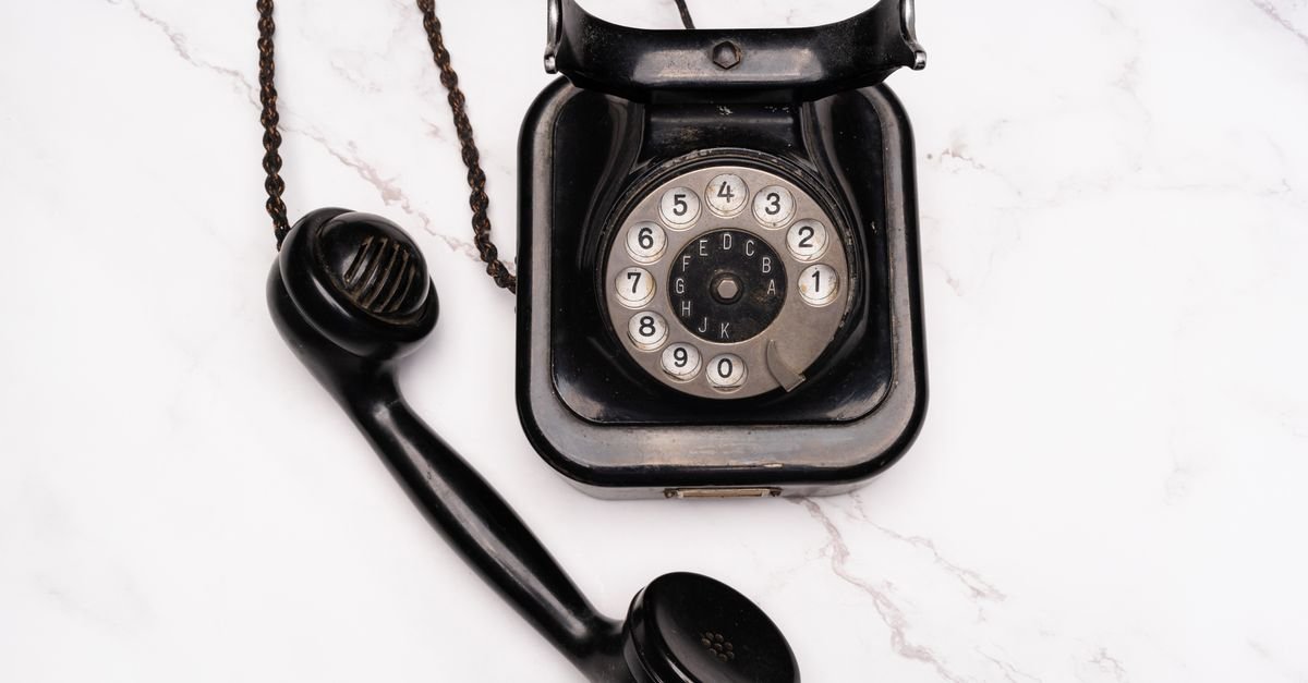 Telefone preto antigo com fone fora do gancho sobre superfície clara