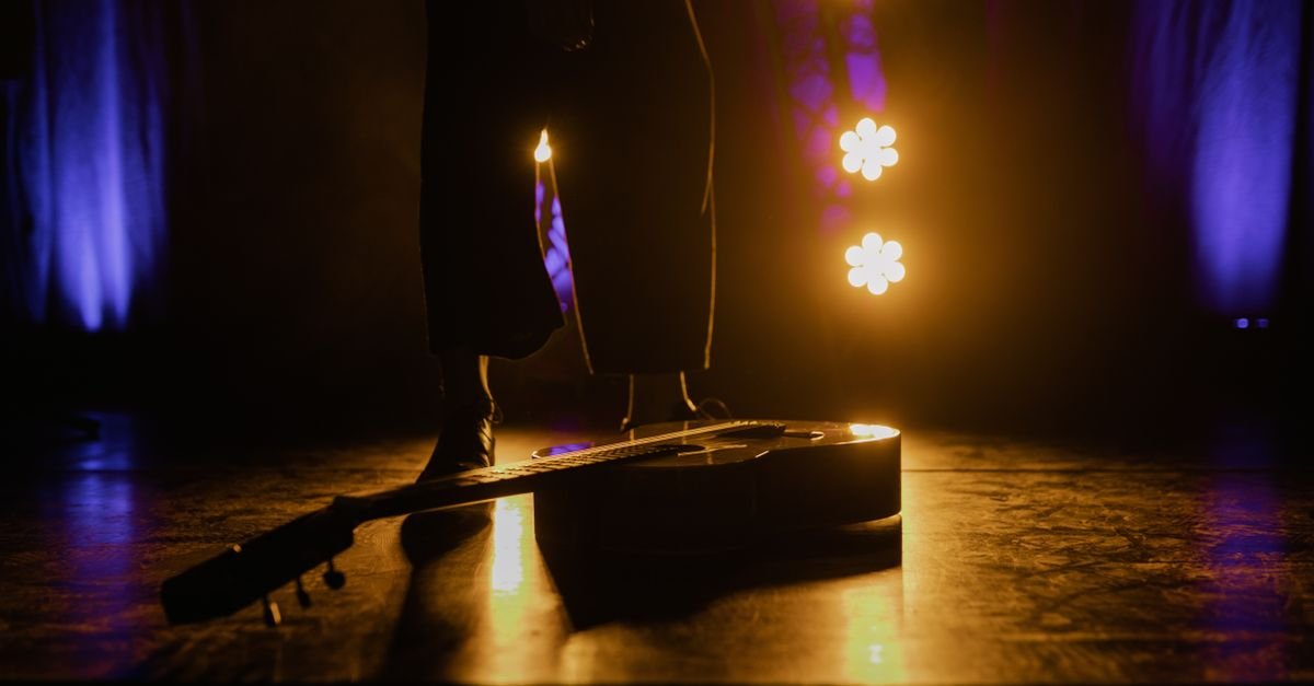 Violão apoiado no palco sob luzes de show