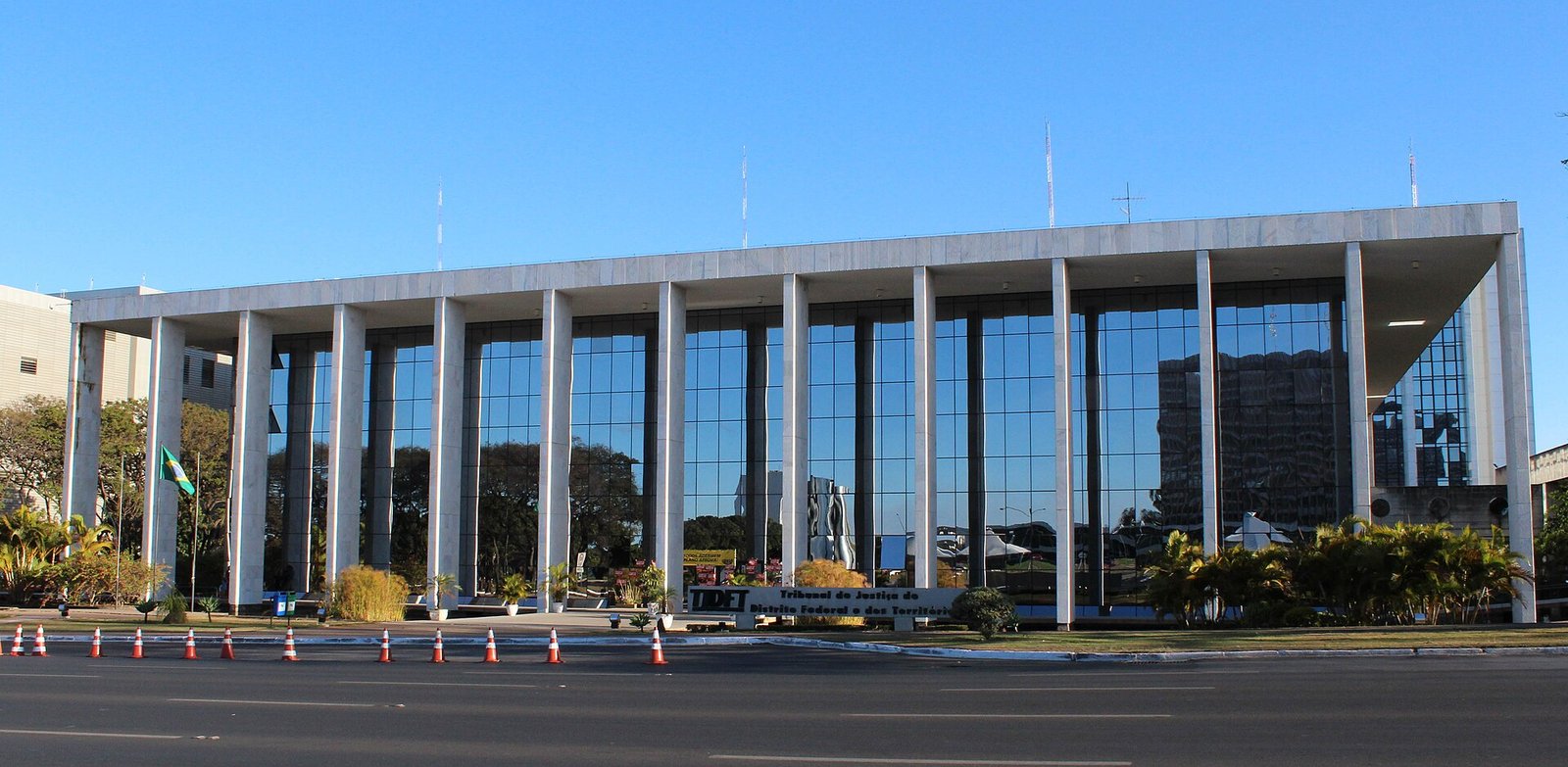 Fachada de vidro do edifício-sede do TJDFT, em Brasília, com cones de trânsito na pista em frente