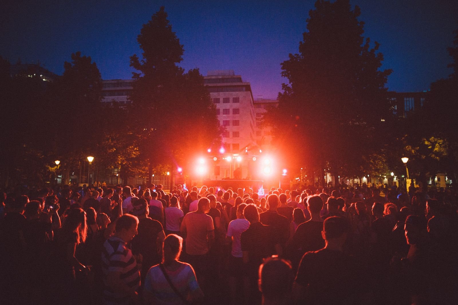 Multidão diante de palco com luzes vermelhas em festa de música eletrônica à noite