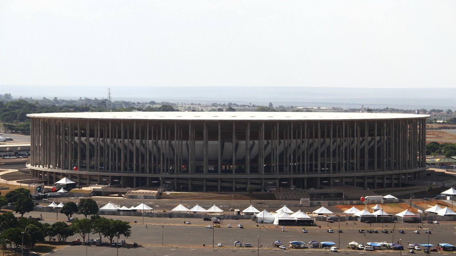 Vista externa da Arena BRB Mané Garrincha, com a fileira de colunas de concreto e o horizonte de Brasília ao fundo