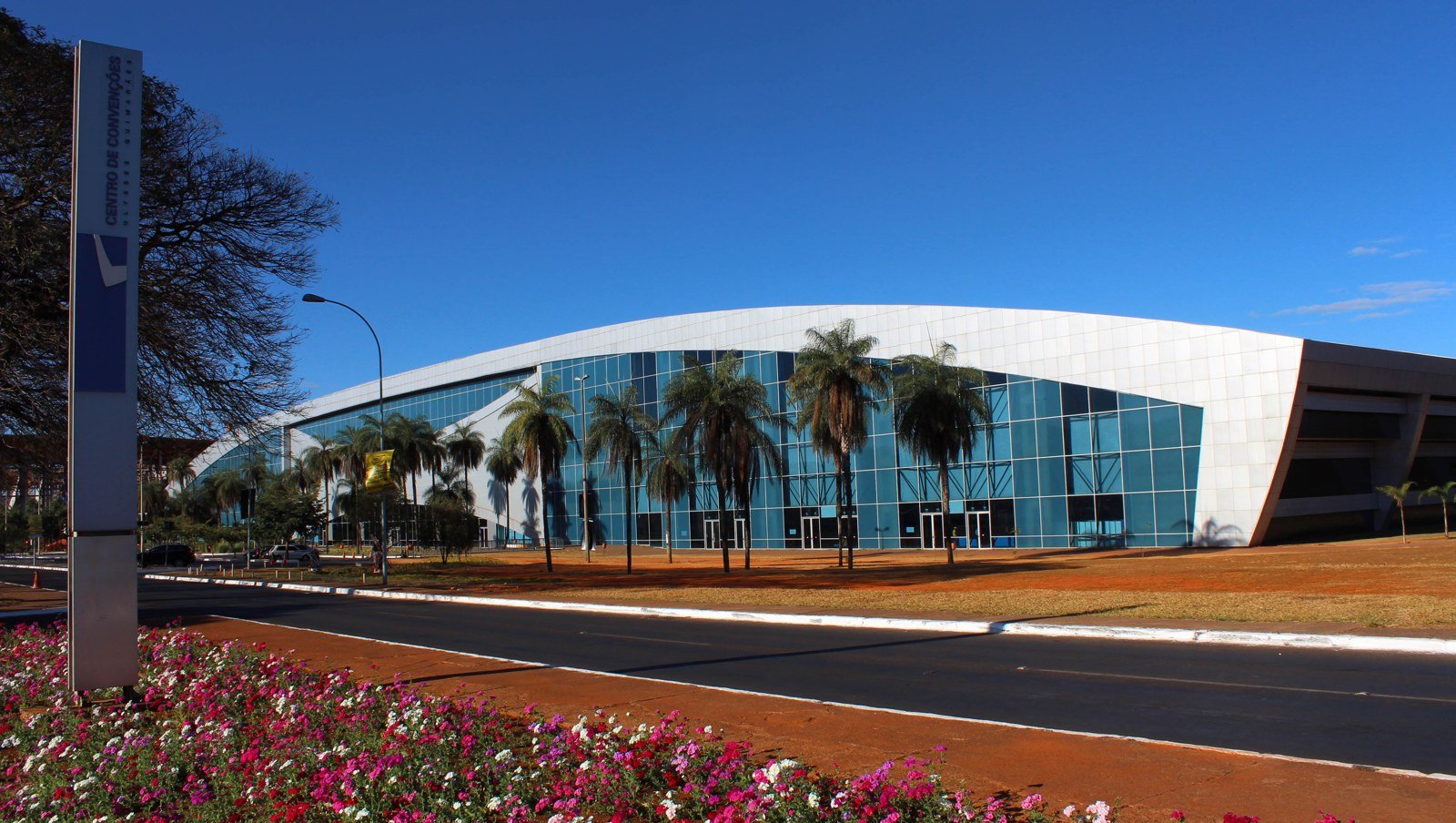 Fachada curva de vidro e painéis brancos do Centro de Convenções Ulysses Guimarães, em Brasília, sob céu azul