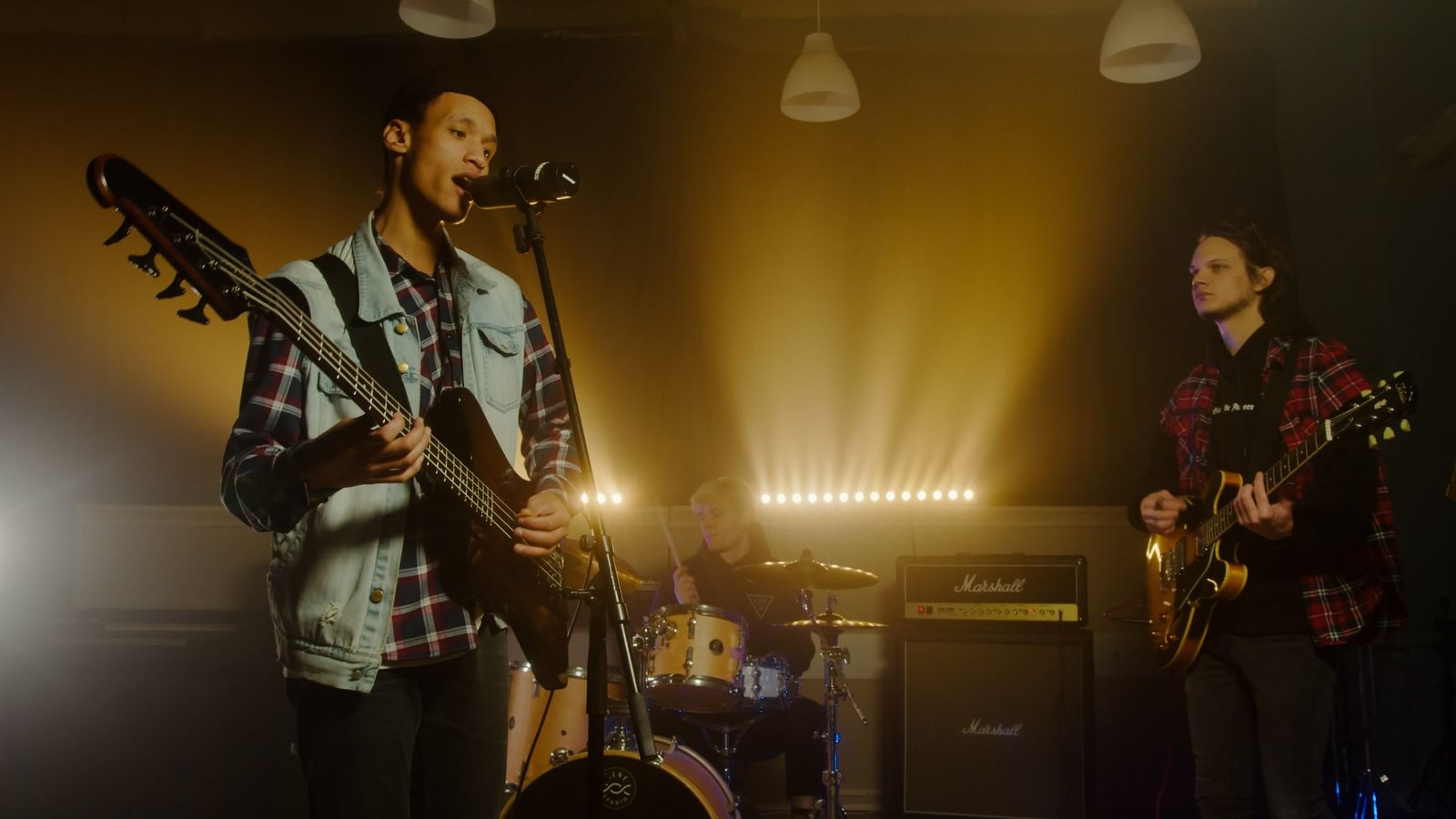 Banda de rock com vocalista, baixista, guitarrista e baterista em palco iluminado (foto de arquivo, não é do evento)