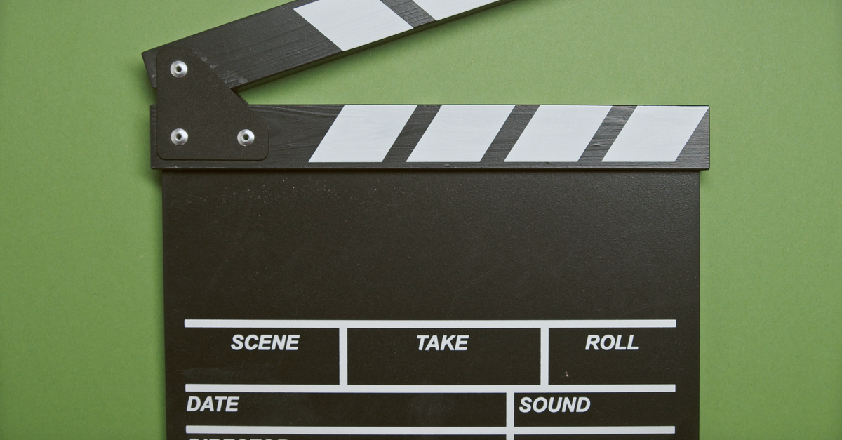 Claquete de cinema aberta sobre fundo verde, com os campos de cena e take em branco