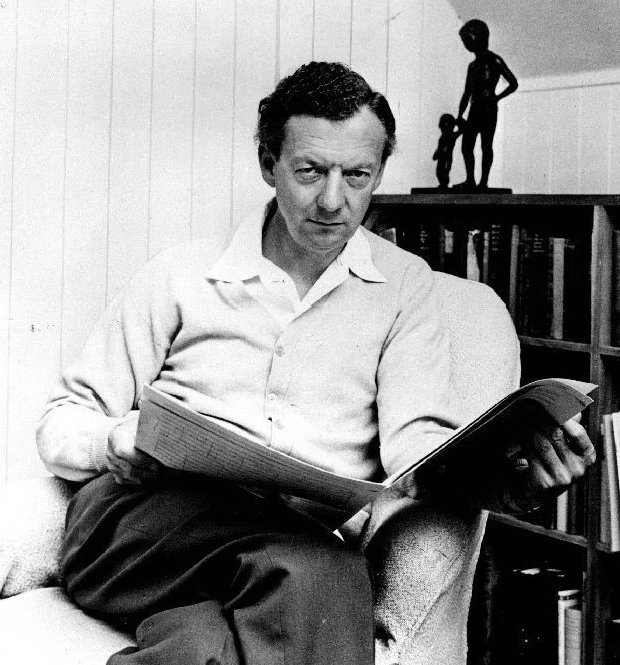 Retrato em preto e branco do compositor Benjamin Britten sentado, com partitura nas mãos