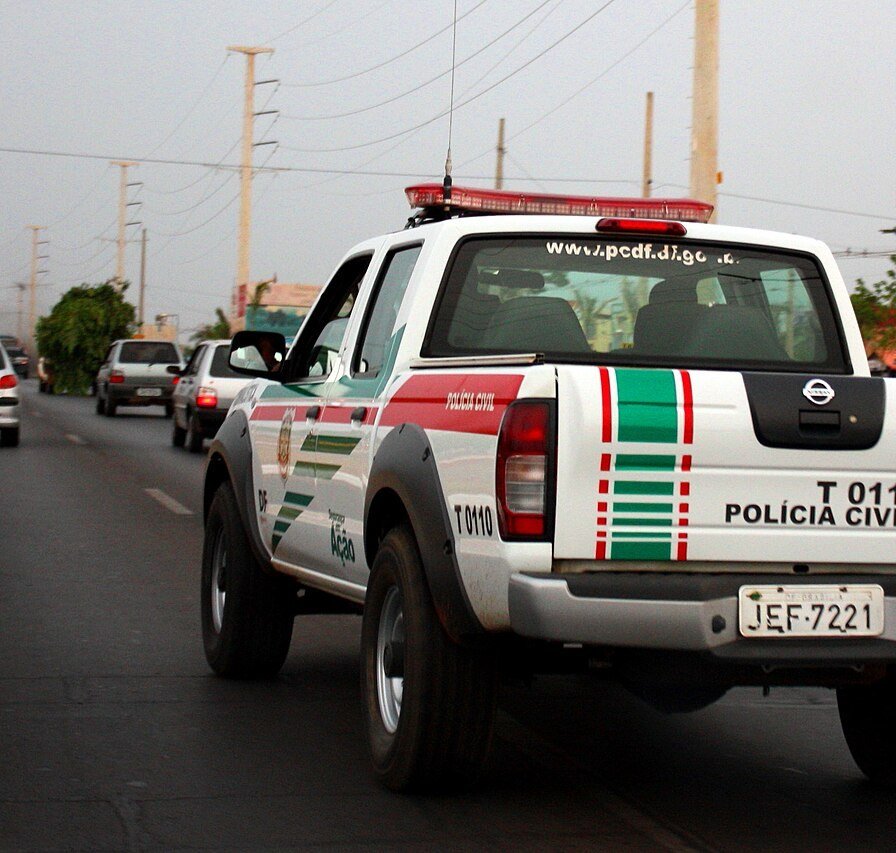 Viatura da Polícia Civil do Distrito Federal, caminhonete branca com faixas verdes e vermelhas, trafegando em via do DF