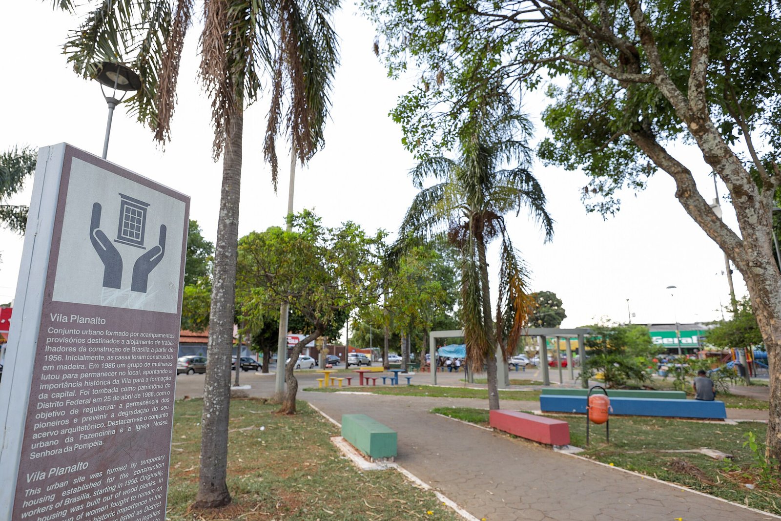 Placa de sinalização da Vila Planalto em praça arborizada do bairro