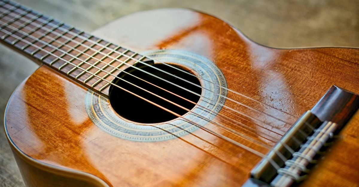 Close de um violão clássico com foco nas cordas e na boca do instrumento