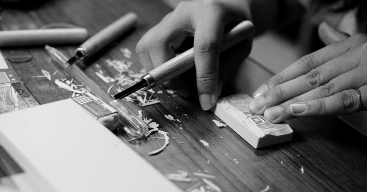 Artesão entalhando matriz de xilogravura, técnica presente na exposição