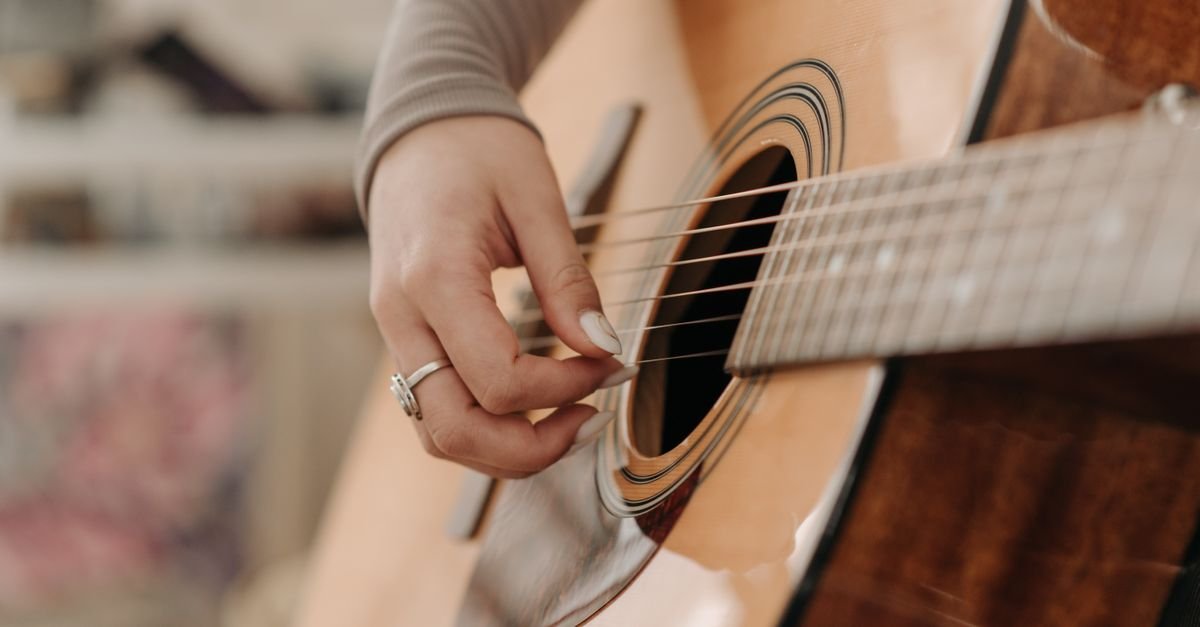 Mão dedilhando as cordas de um violão em close, em imagem ilustrativa